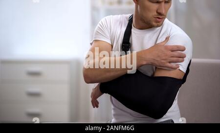 Man wearing arm sling feeling pain in shoulder, result of trauma, orthopedics Stock Photo