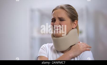 Upset girl in foam cervical collar suffering pain in shoulder, accident injury Stock Photo