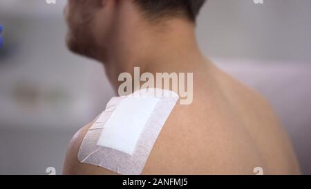 Adhesive bandage applied on male injured shoulder, first aid, household injury Stock Photo