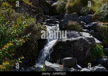 Dark wet rocks have white water running through them Stock Photo