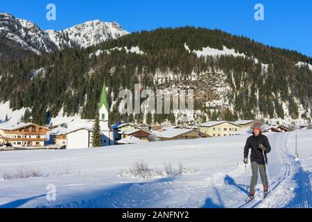 Hochfilzen: woman cross-country skiing, view to Hochfilzen and mountain Loferer Steinberge (Lofer Mountains) in Kitzbüheler Alpen - Pillersee Tal, Tir Stock Photo