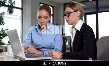 Experienced manager teaching trainee in office, explaining project on laptop Stock Photo