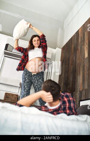 Beautiful pregnant couple in the bedroom. Preparing for childbirth, happy parents, waiting for the first child. Support for women before childbirth Stock Photo