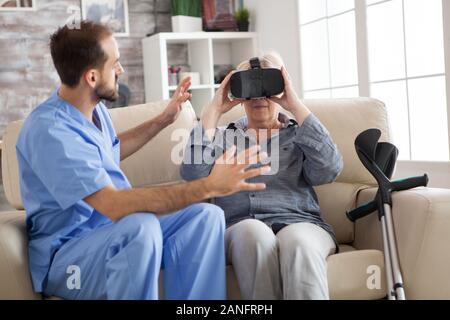 Older patient using virtual reality glasses in nursing home to see her spine. Stock Photo