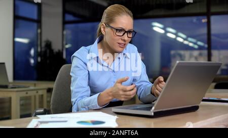 Businesswoman irritated using stuck laptop, mad about data loss, software error Stock Photo