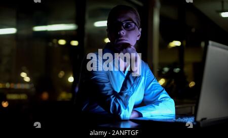 Businesswoman thinking of difficult business project, working extra hours, night Stock Photo
