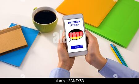 German language application on smartphone in persons hands, online education Stock Photo
