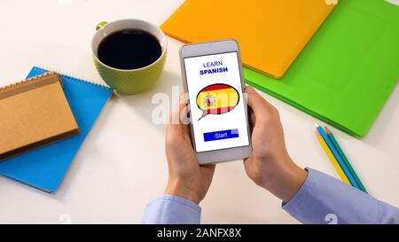 Learn Spanish application on cellphone in persons hands, studying language Stock Photo