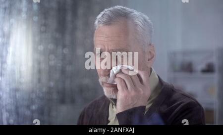 Upset retired man crying at home, thinking of problem, sad memories, depression Stock Photo