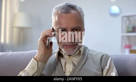 Glad pensioner talking on phone with close relatives, cheap mobile provider Stock Photo