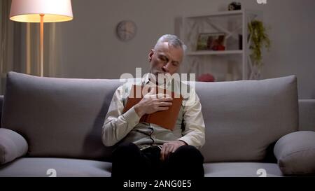 Elderly man sleeping on couch with book in hands, leisure time on weekends Stock Photo