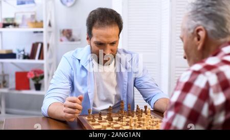 Adult males playing chess, father and son competing, hobby and leisure activity Stock Photo