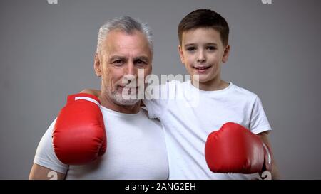 Active senior male and boy in boxing gloves looking to camera, healthy lifestyle Stock Photo