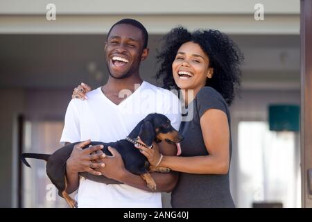 Portrait of excited black family posing with dog near home Stock Photo
