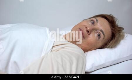 Senior woman lying on bed, preparing to cosmetological procedures, beautician Stock Photo