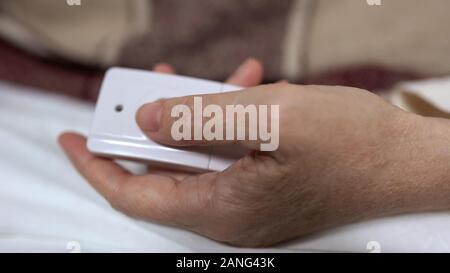 Female patient pushing nurse call button or taking extra dose of pain reliever Stock Photo