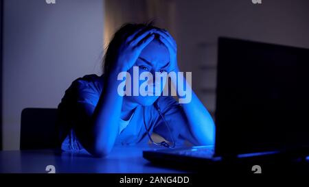 Tired young doctor working on computer at night, preparing for examination Stock Photo