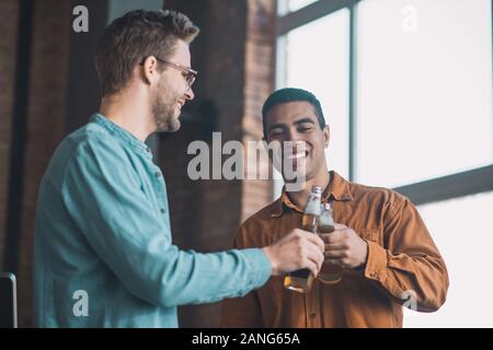 Positive happy friends cheering with bottles of beer Stock Photo
