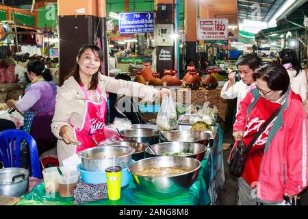 Nan, Thailand - December 16th 2014: Smiling food vendor serving customers on the market. A market is held every day in the town centre. Stock Photo