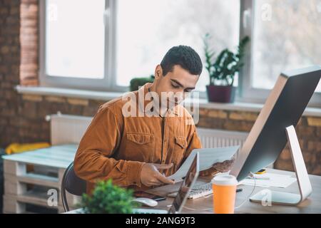 Nice serious young man focusing on his project Stock Photo