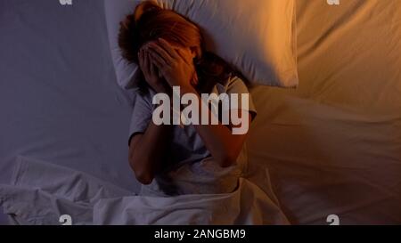 Woman hiding face while lying in bed, cant wake up in morning, tedious sleep Stock Photo