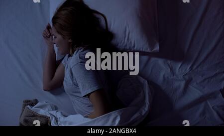 Lady feeling sharp stomachache during sleeping, suffering from cystitis illness Stock Photo