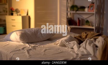 Messy bed, white pillow with blanket lying on bed unmade, oversleeping concept Stock Photo