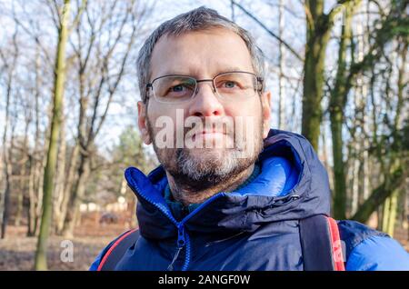 Portrait of a man in a phantom blue down jacket in the barren spring forest Stock Photo