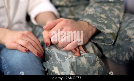 Male soldier holding girlfriends hand, farewell before military service, love Stock Photo