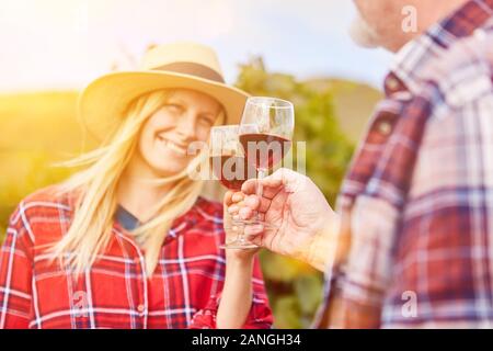 Happy couple with glass of red wine having wine tasting and tasting in vineyard Stock Photo