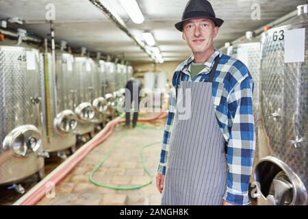 Wine master or master brewer in the winery or brewery with fermentation tanks Stock Photo