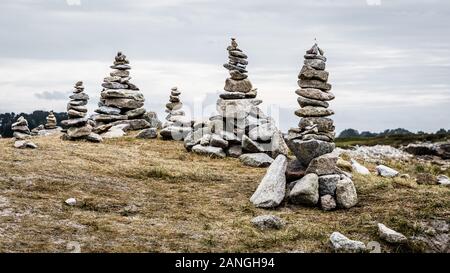 Several man-made granite stone stacks (called cairns) on the coastal path in Brittany, France, on a cloudy day. Stock Photo