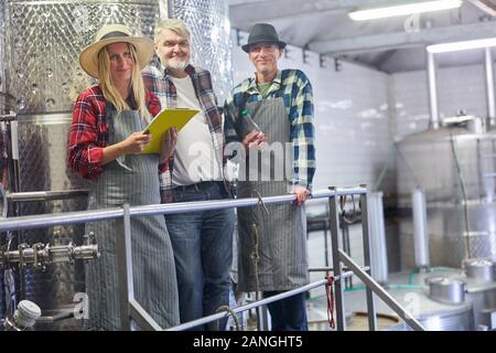 Winery team with cellar master and trainee with checklist at the fermentation tank Stock Photo