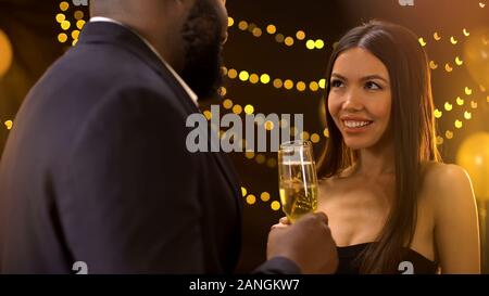 Joyful mixed-race couple flirting at corporate event, new year party celebration Stock Photo
