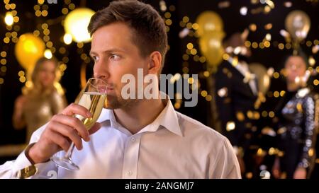 Sad caucasian male drinking champagne feeling lonely celebration event, bad mood Stock Photo
