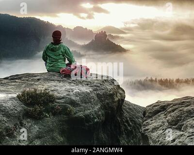 Back silhouette of hiker woman admiring amazing landscape over misty mountains in sunset time. Stock Photo