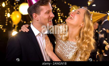 Happy couple in party hats laughing and having fun, celebrating birthday Stock Photo