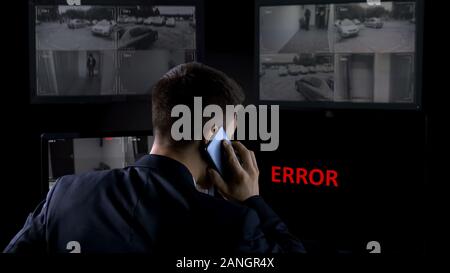 Security operator calling police, error on screen of CCTV footage, robbery Stock Photo