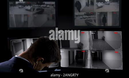 Security guard sleeping in front of surveillance camera, twenty-for-hour work Stock Photo