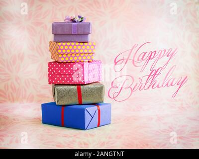 five colourful square gift boxes with happy birthday text, soft pink background Stock Photo