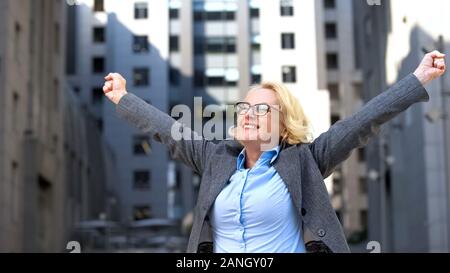Glad office worker with raised up hands enjoying career success, achievement Stock Photo