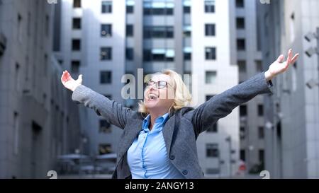 Optimistic elderly female raised hands enjoying life, business success, vitality Stock Photo