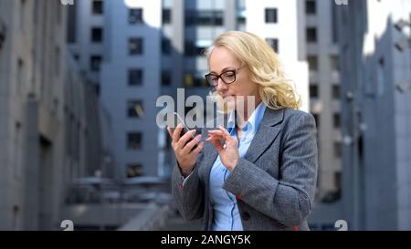 Mature company employee in formal suit using business organizer smartphone, app Stock Photo