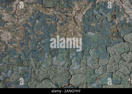 Bumpy layers of damaged blue greenish paint peeling .Old weathered crackled painted wall abstract texture. Stock Photo