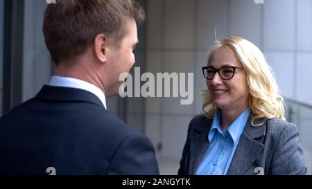 Smiling male and female business partners looking each other, company colleagues Stock Photo