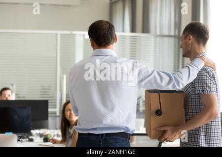 Back view of company employer introduce new male employee to colleagues in office, businessman or CEO acquaint newcomer holding belongings with cowork Stock Photo