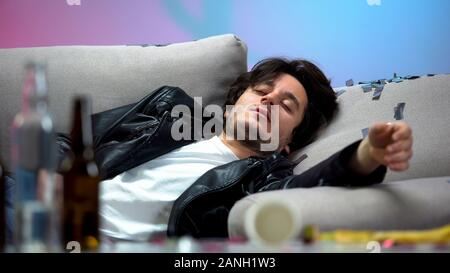 Drunk young man sleeping on couch after night long party, idle life, hangover Stock Photo