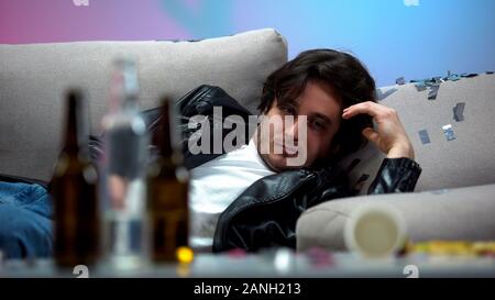 Hangover man waking up in messy room after night party, drunkard idle lifestyle Stock Photo