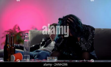 Junky couple feeling unwell, sitting on coach in club, drugs overdose risk Stock Photo