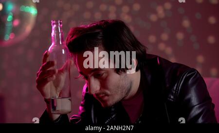 Man holding vodka bottle, trying to escape problems using alcohol, addiction Stock Photo